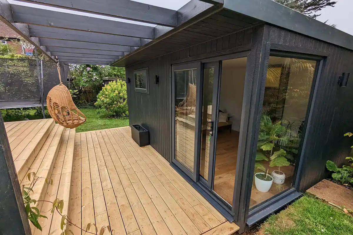 Contemporary garden room clad in Granite coloured ToughWood with a large decking area with pergola 